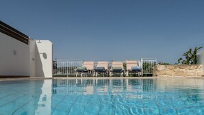 A clear blue pool with lounge chairs and a stone wall in the background. - up to 20 pax Myrtia Villa & Cave Estate with Pool & Hot tub by Chic Greek Villas (Myrtia)