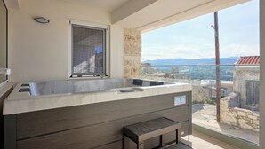 A modern bathroom with a large bathtub, a window, and a view of the surrounding landscape. - up to 20 pax Myrtia Villa & Cave Estate with Pool & Hot tub by Chic Greek Villas (Myrtia)