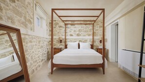 A bedroom with a four-poster bed, stone walls, a wooden nightstand, and a bedside table with a lamp. - up to 20 pax Myrtia Villa & Cave Estate with Pool & Hot tub by Chic Greek Villas (Myrtia)