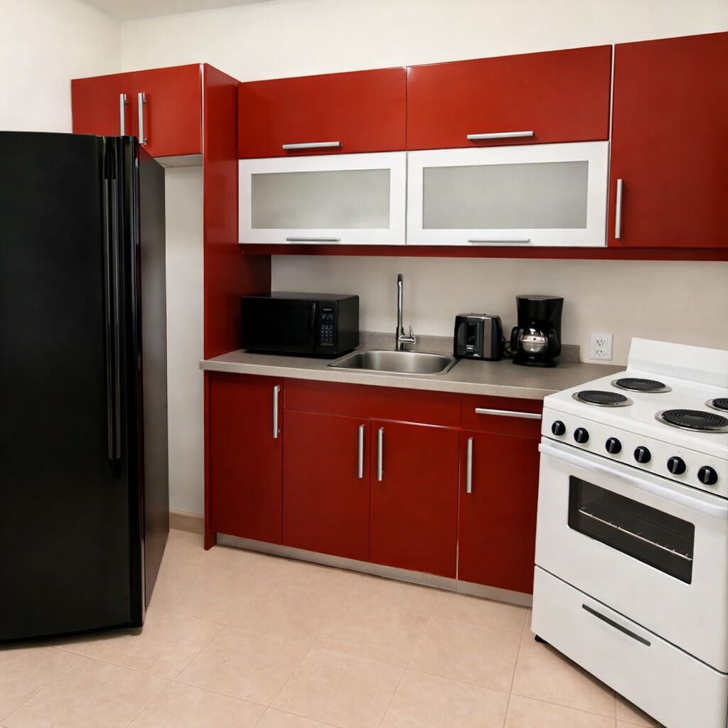 A kitchen with red cabinets, a black refrigerator, a microwave, a coffee maker, and a stove.