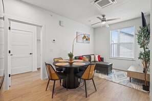 Una sala de estar moderna con una mesa de comedor, sofá y ventilador de techo.