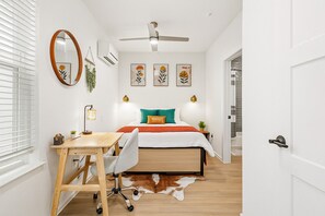Un dormitorio con cama, escritorio, silla y alfombra de cuero de vaca.