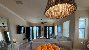 Ein geräumiges Wohnzimmer mit einer großen Couch, einem Essbereich mit Tisch und einer Küchenzeile mit Obstschale.