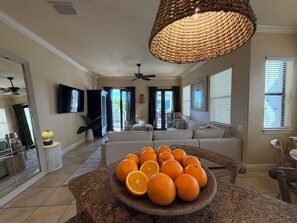 A spacious living room with a large sofa, a dining area with a table, and a kitchen area with a fruit bowl. - Last Minute Availability Siesta Key Dream 100 ft to Beach Walk Everywhere (Siesta Key)
