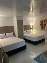 Habitación de hotel con dos camas, un armario y un cuadro en la pared.