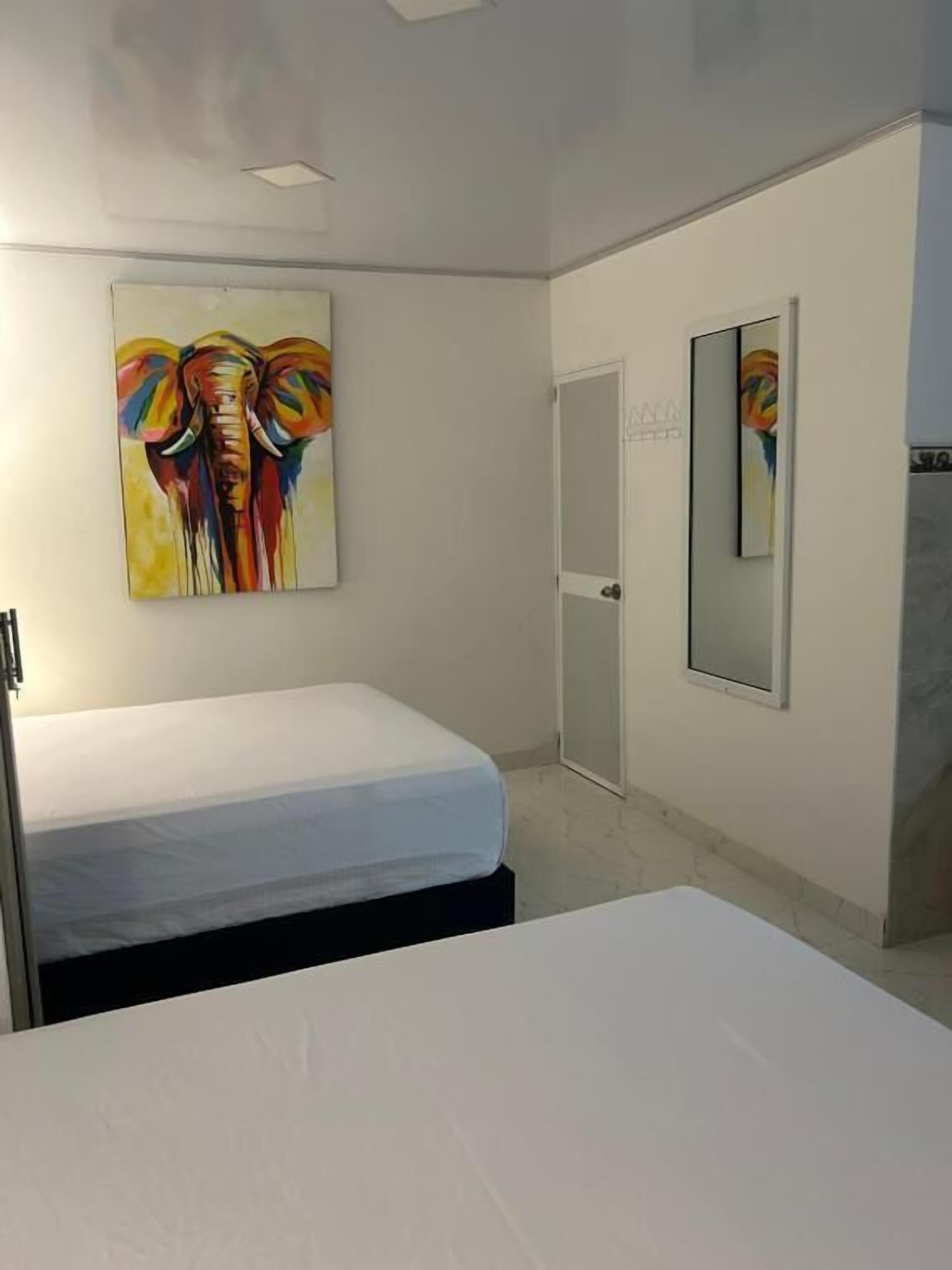 Une chambre à coucher avec un lit, une porte et deux tableaux accrochés au mur.