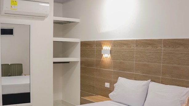 Ein Hotelzimmer mit Bett, Nachttisch, Wandleuchte und eingebautem Regal.