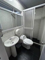 Un baño con lavamanos, inodoro y cabina de ducha.
