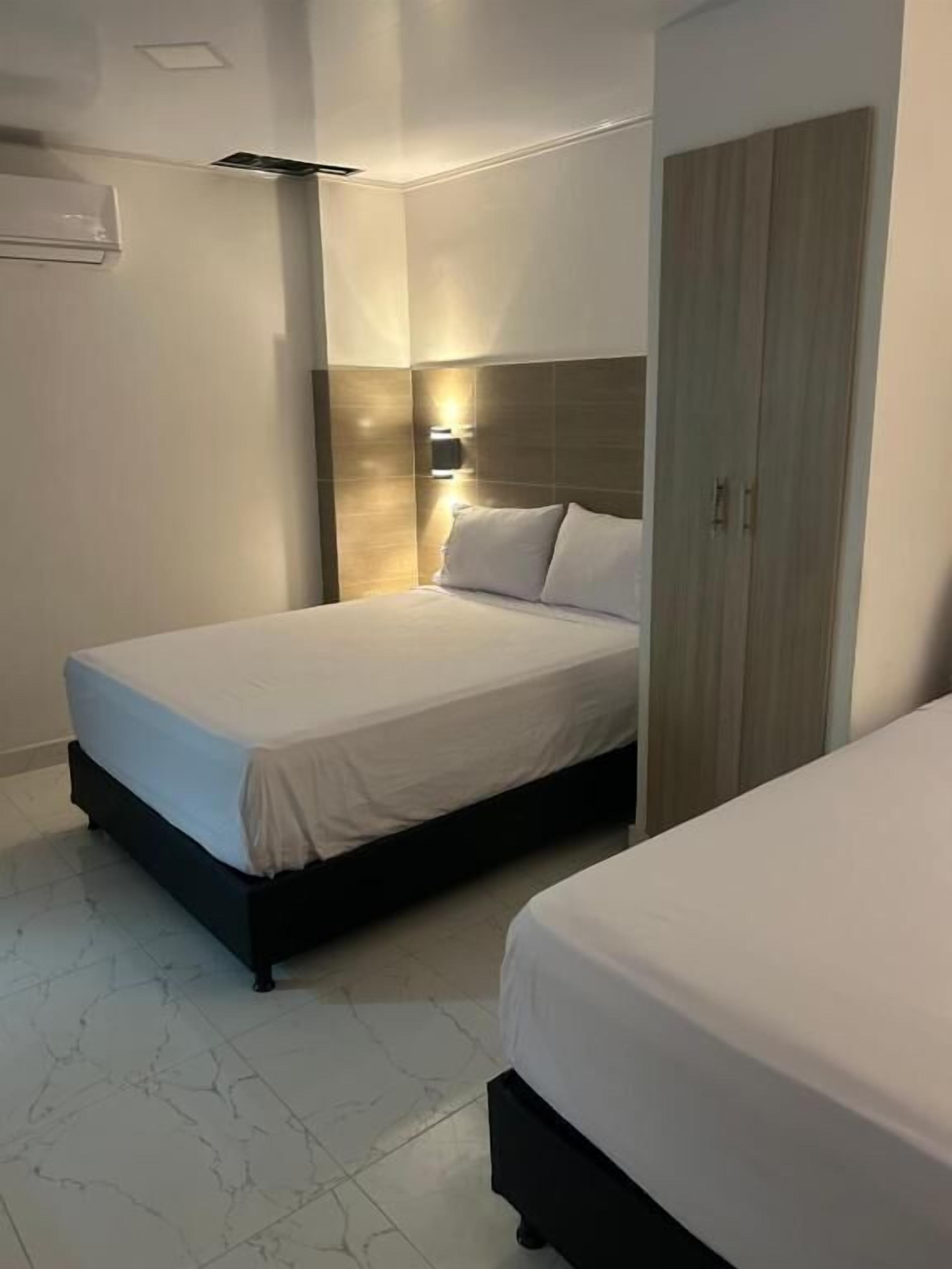 Une chambre d’hôtel équipée d’un lit, d’une armoire et d’un luminaire fixé au mur.