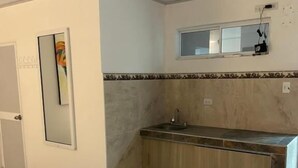 A hotel room with a bed, a small kitchenette with a sink, and a mirror above the countertop. - Hotel Brisas del Mar Rodadero (Santa Marta)