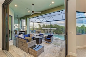 A spacious living area with a large glass door leading to a pool, wicker furniture, and a ceiling fan. - Waterfront private Resort style in South Gulf Cove, heated pool, spa & boat dock (Port Charlotte)