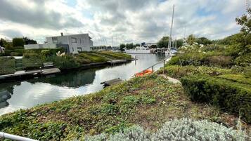 Een gracht met boten, een modern gebouw en weelderige begroeiing.