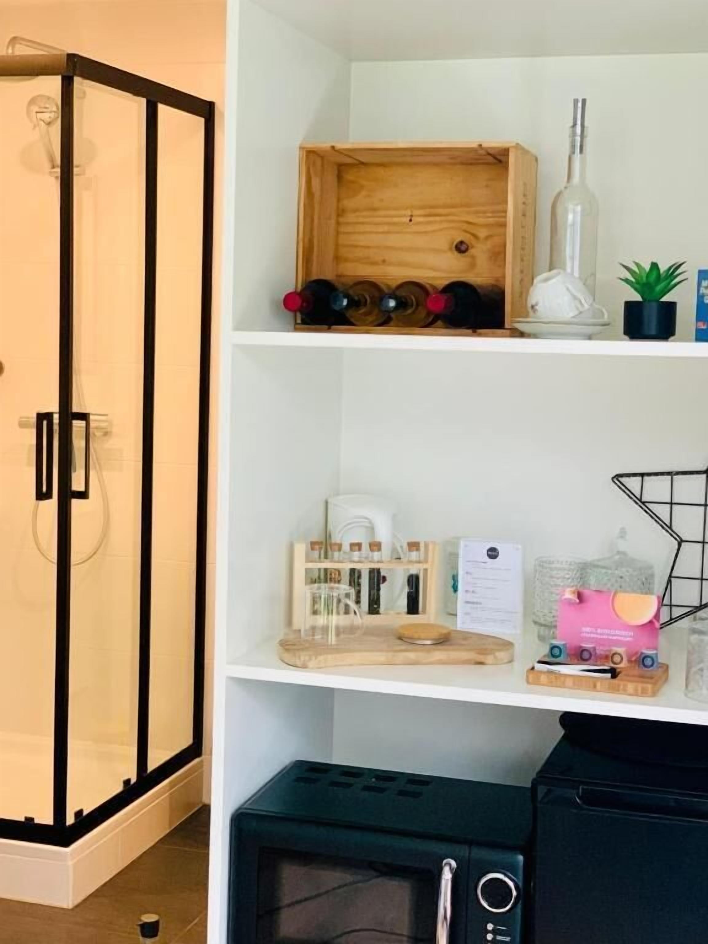 Una zona de cocina equipada con microondas, cafetera y estante para vinos.