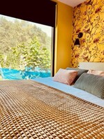 Un dormitorio con una cama grande, vistas a espacios verdes y un papel tapiz floral.