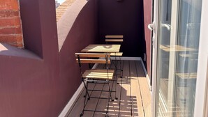 A small outdoor patio with a wooden table and benches, a glass door, and a red brick wall. - Maximo Mexico Roma (Mexico City)