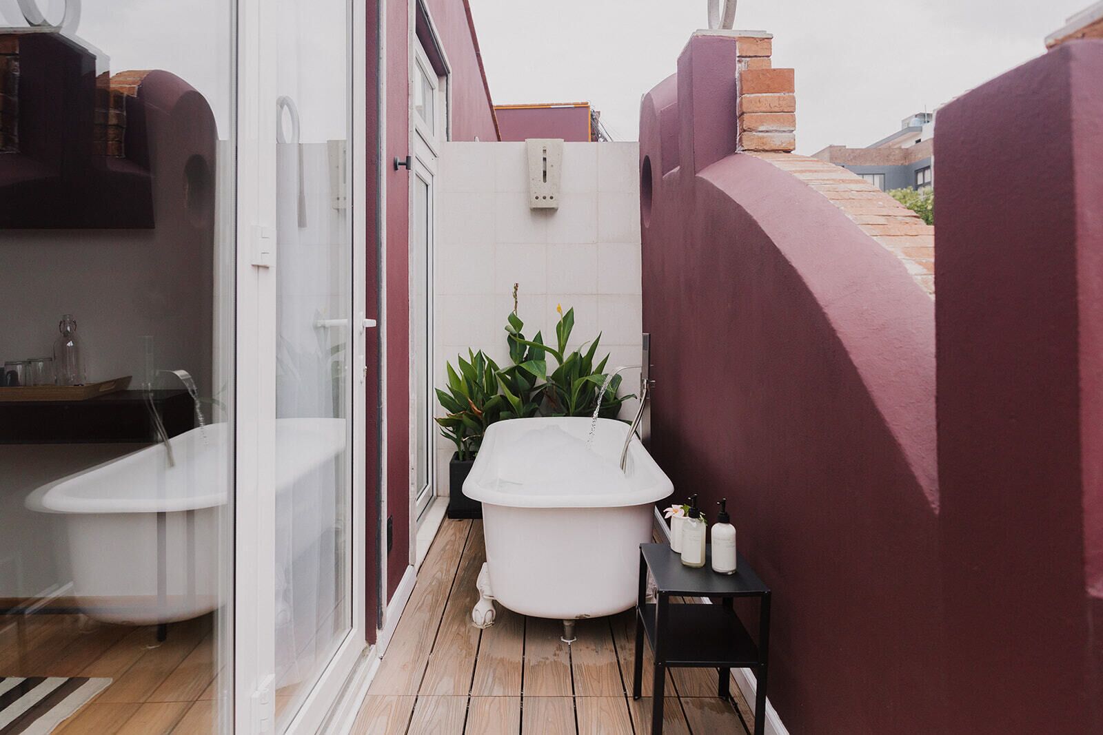 A modern bathroom with a freestanding bathtub, a shower, and a small table with toiletries.