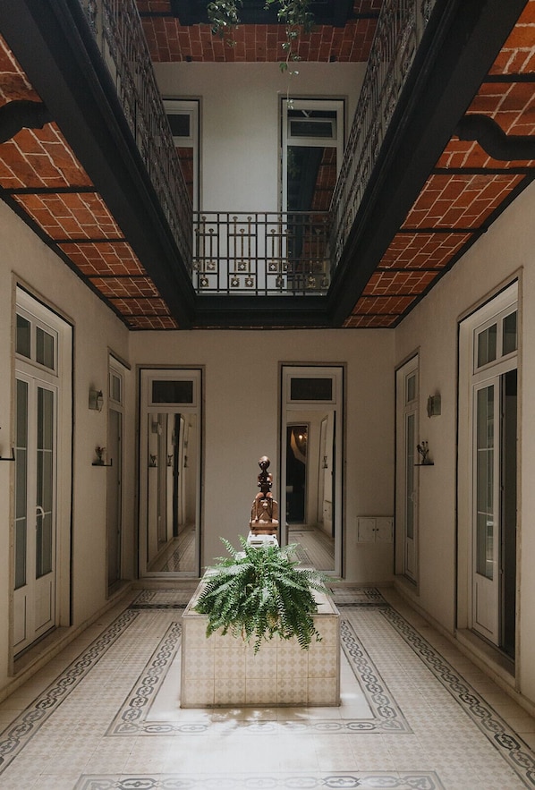 A corridor with a central planter, mirrored walls, and a balcony with a railing. - Maximo Mexico Roma (Mexico City)