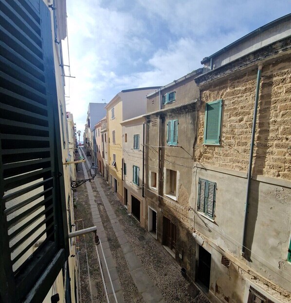 Una calle estrecha con edificios de fachadas de piedra y numerosas ventanas con contraventanas.