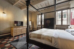 A bedroom with a four-poster bed, a television, a dresser, and a radiator. - Eleganza Antica by MMega (Florence)