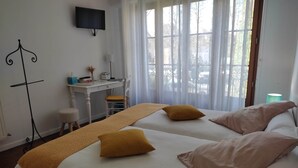 A hotel room with two beds, a desk, a chair, and a TV on the wall. - Colorful Room - ASPE (OLORON STE MARIE)