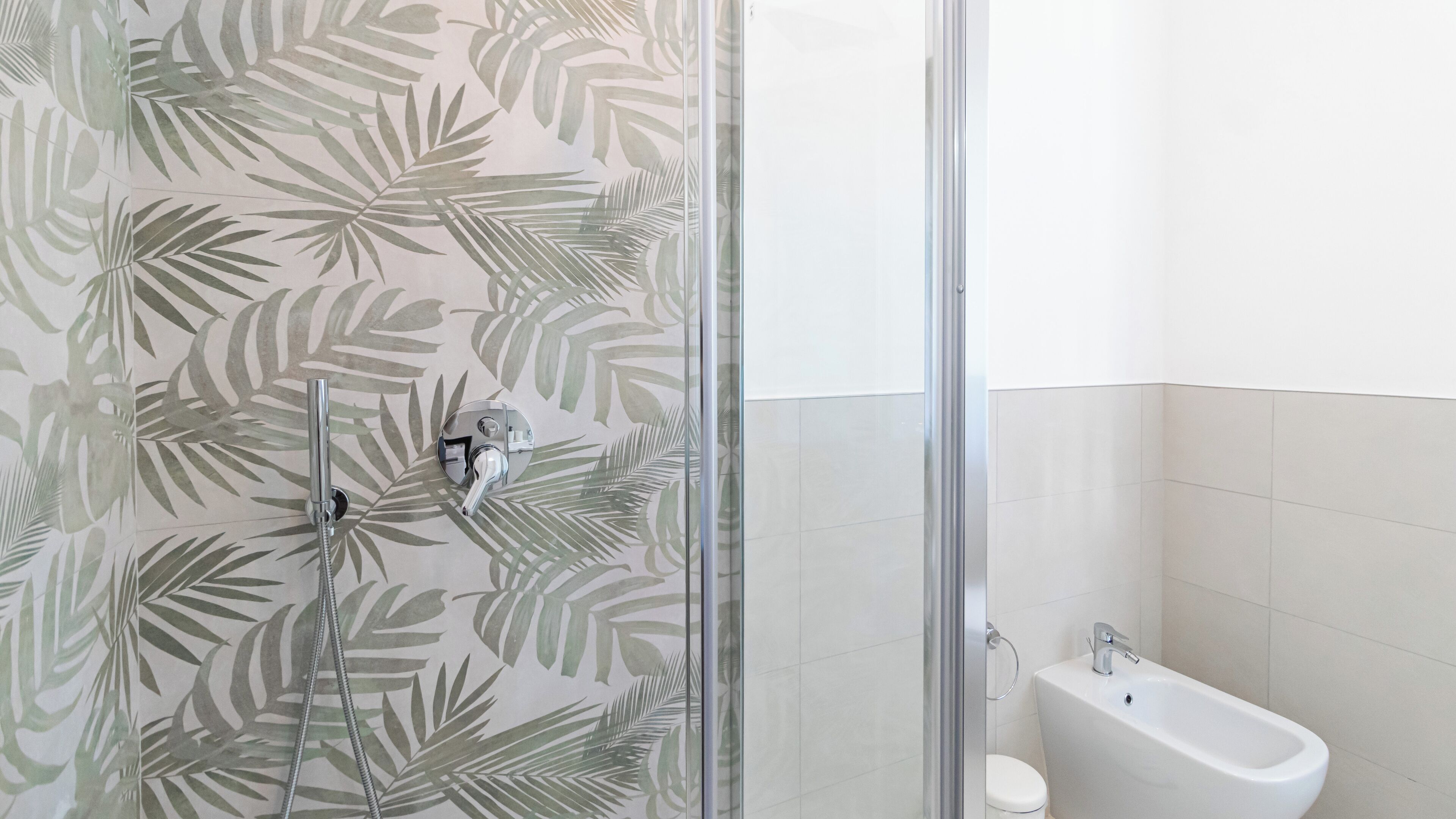 A bathroom with a shower enclosure featuring a glass door, a toilet, and a sink.