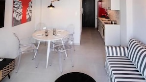 Un espace de vie moderne et ouvert, comprenant un coin repas, une table ronde noire et un canapé à rayures.