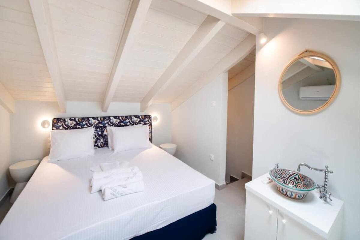 Une chambre à coucher comprenant un lit, une table de chevet et une salle de bain avec un lavabo et un miroir.