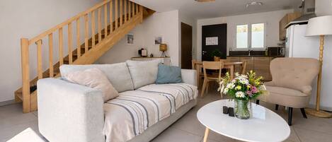 A living room with a sofa, a coffee table, a chair, a dining table, and a staircase.