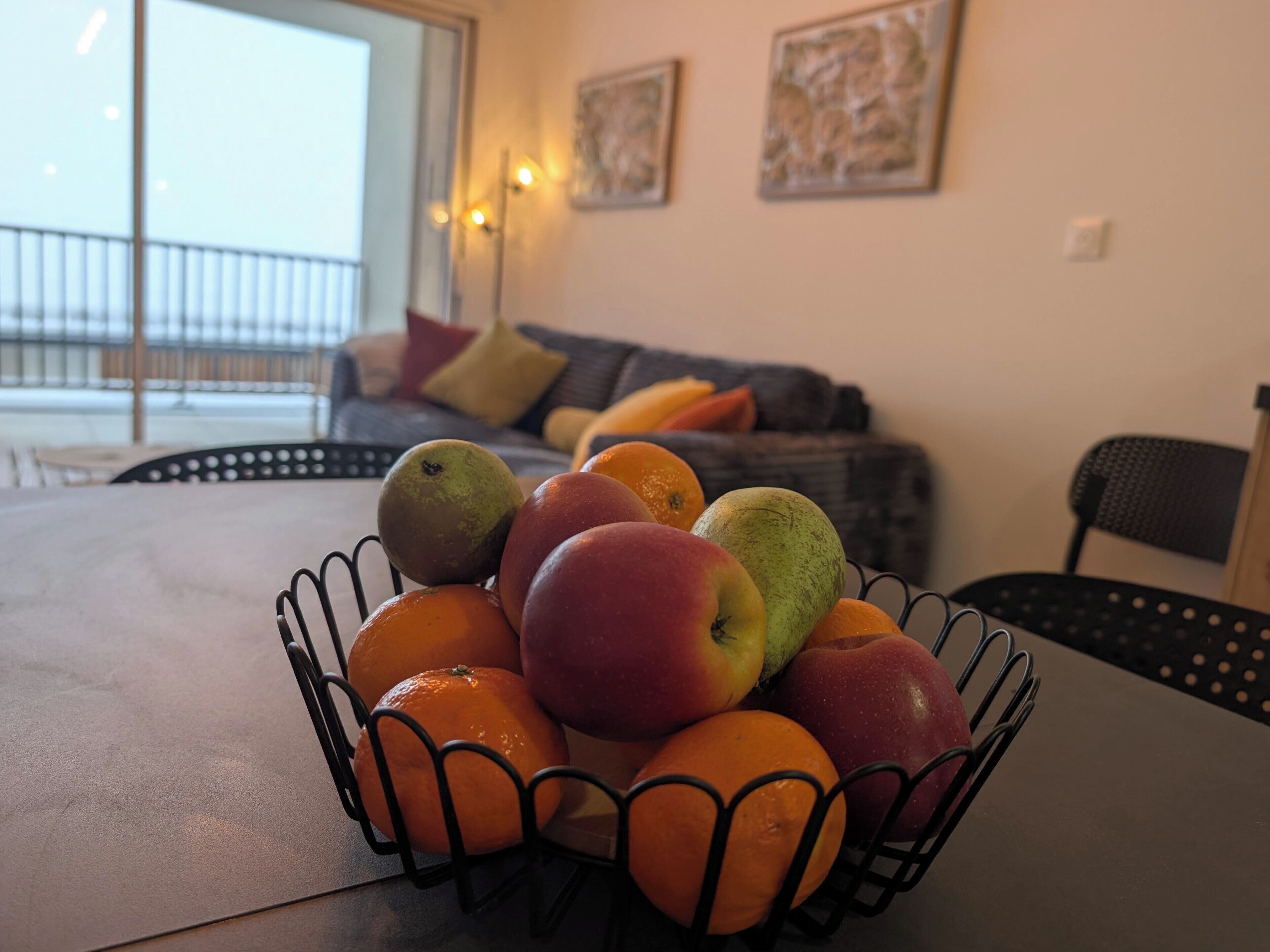 A fruit bowl on a table with oranges and apples.