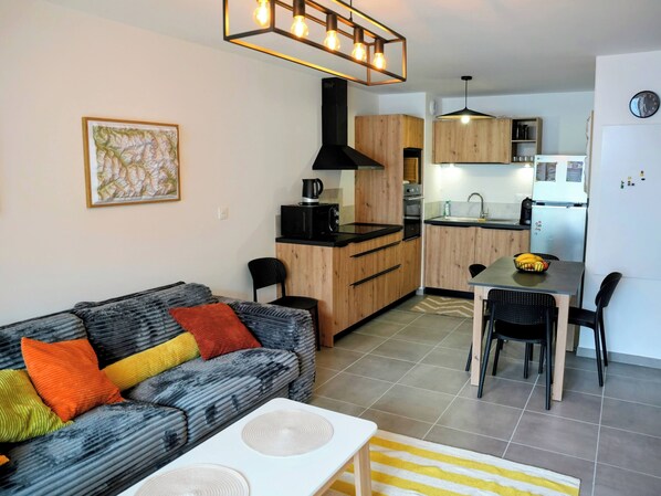 A compact living space with a sofa, a dining table, and a kitchen area. - Modern apartment close to the slopes in Briançon (Briançon)