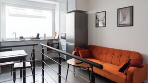 Et moderne køkken med spiseplads, sofa og trappe.