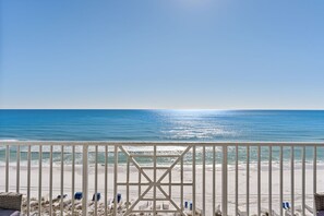 Une vue sur la plage depuis un balcon doté d’une balustrade, avec une plage de sable et l’océan en toile de fond.