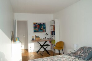 Ein Schlafzimmer mit Bett, Schreibtisch, Stuhl, Bücherregal und einer Tür.