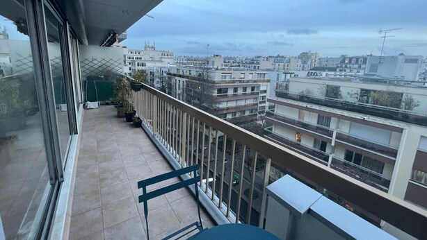 Un balcón con vista a un paisaje urbano, que incluye edificios y una carretera.