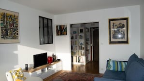 Una sala de estar con un sofá, una mesa de centro, un televisor y una estantería.