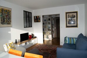 Ein Wohnzimmer mit einer Couch, einem Couchtisch, einem Fernseher und einem Bücherregal.