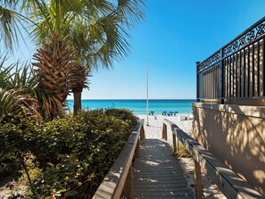 A wooden pathway leading to a beach with a palm tree and a fence on the right. - Upscale Home, Close to Beach (Destin)