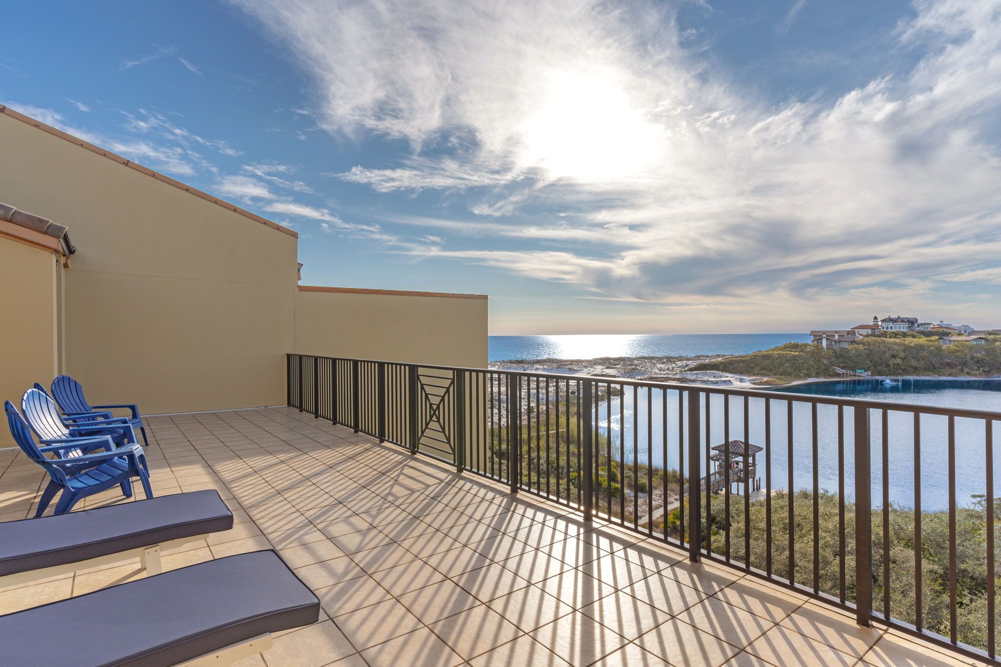 A balcony with a view of the sea and a distant building.