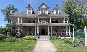 Un edificio de dos pisos con una entrada central, un porche con barandillas y un letrero que indica 'The Berkshire Mountain Inn'.