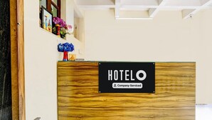 A reception desk with a wooden panel and a sign that reads "HOTEL Company-Serviced". - Super Hotel O Benaulim Beach Goa (Benaulim)