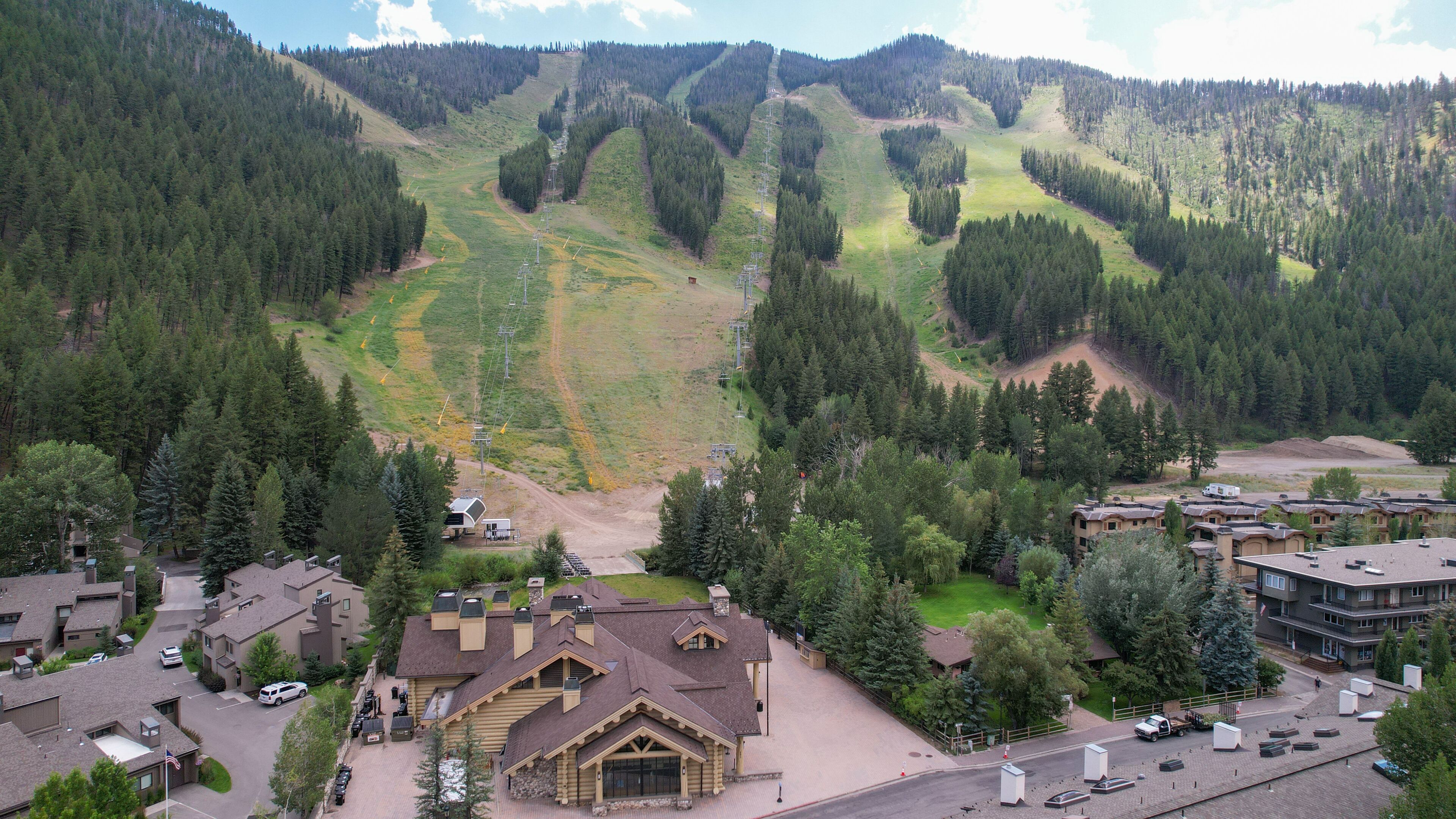 A lodge with a mountain view, a parking area, and a ski lift in the background.