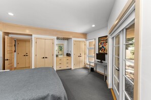 Ein Schlafzimmer mit Bett, Schreibtisch, Fernseher und Fenster.