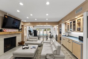 Ein modernes Wohnzimmer mit Flachbildfernseher, Sofas, Couchtisch und Kamin.