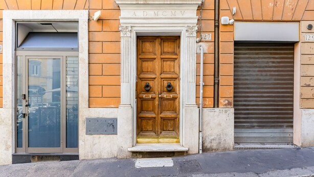 A building facade with a wooden double door, a glass door, and a closed metal shutter. - BDC - Trevi Premium 3BDR + 3BATH (Rome)