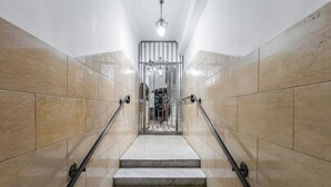 A marble staircase with handrails, leading to a door with a decorative gate. - BDC - Trevi Premium 3BDR + 3BATH (Rome)