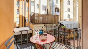 A balcony with a red table, a bottle of Gordon's Gin, and a glass of water. - BDC - Trevi Premium 3BDR + 3BATH (Rome)
