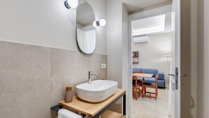 A modern bathroom with a large mirror, a white sink, and a wooden vanity. - BDC - Trevi Premium 3BDR + 3BATH (Rome)