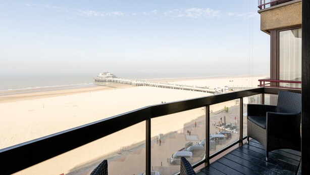 Ein Balkon mit Blick auf Strand und Steg.