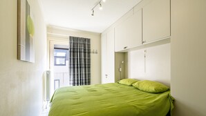Ein Schlafzimmer mit Bett, Fenster mit Vorhängen und einer Tür.