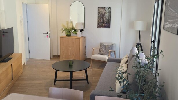 A modern living room with a sofa, a round table, a TV, and a cabinet. - Modern Duplex in the Heart of Jaca for 6 People (Jaca)